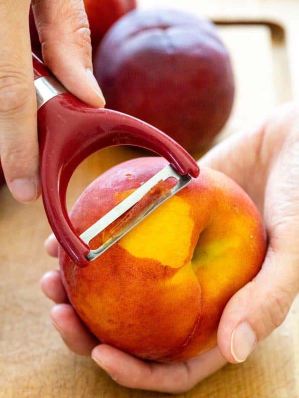 Using vegetable peeler to peel peach skin